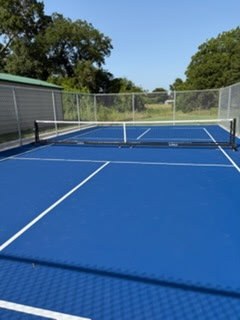 Blue outdoor court with a net and perimeter fencing