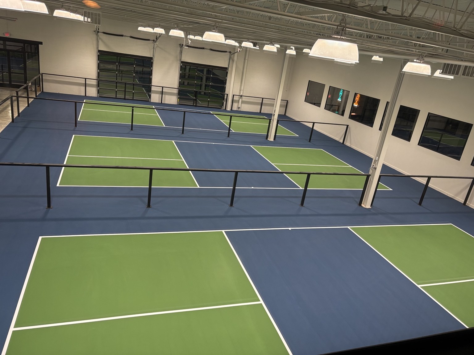 Indoor pickleball courts with green playing areas and blue surrounds