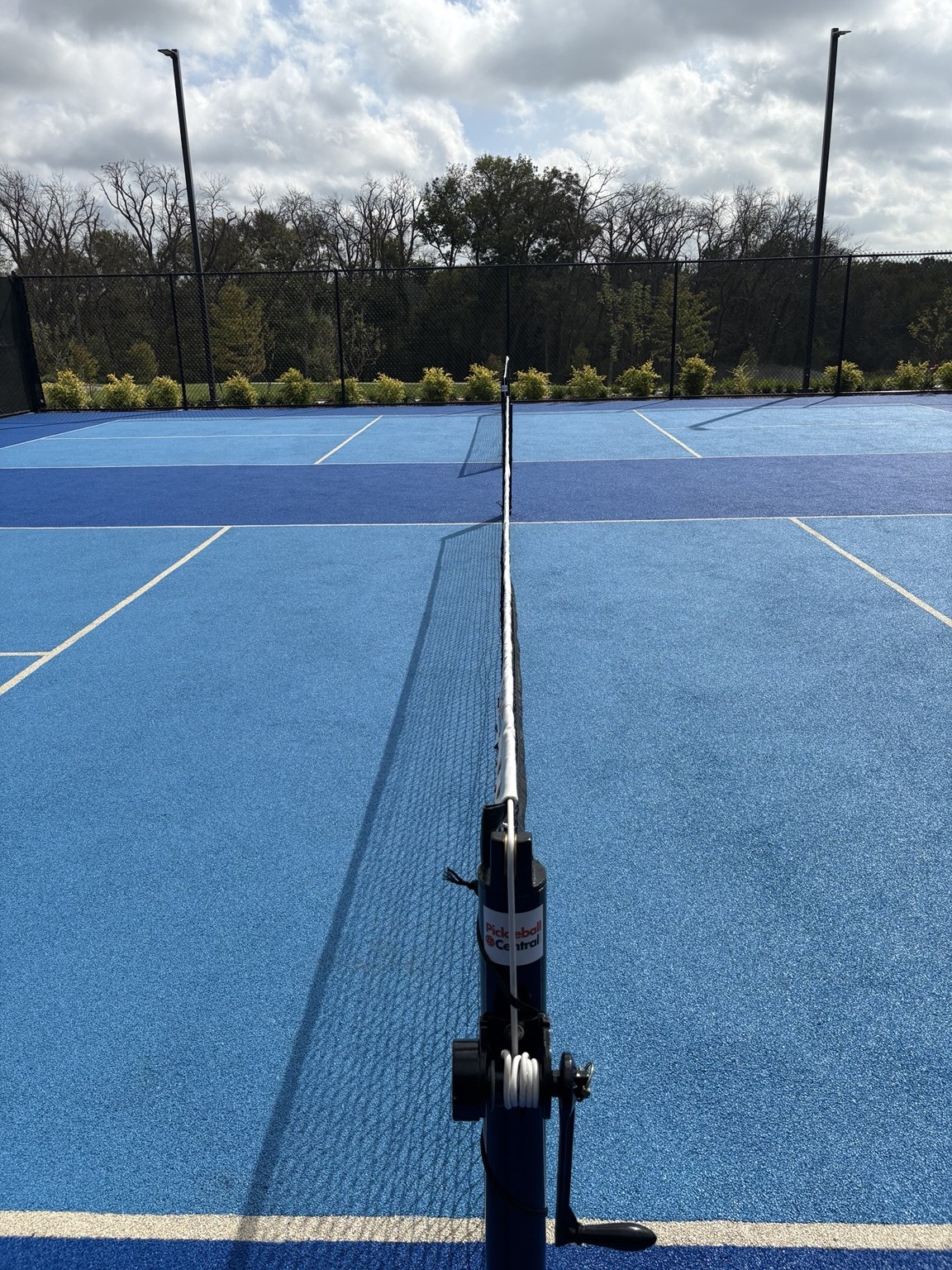 Blue rubber pickleball court beside a permanent net